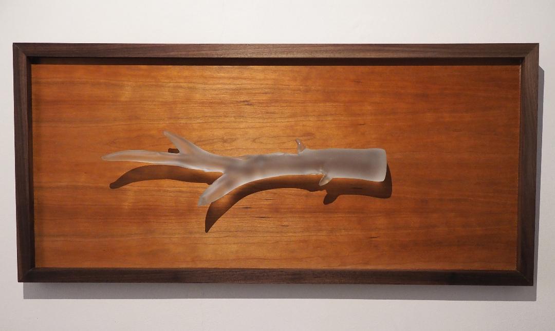 A frosted glass antler laid in a walnut frame